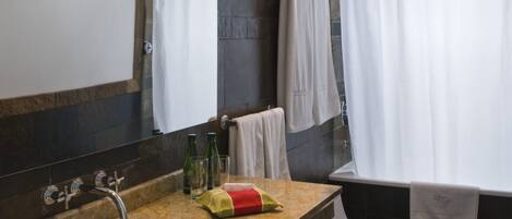 A bathroom with a stone countertop sink, a mirror, a toilet, and a shower curtain.