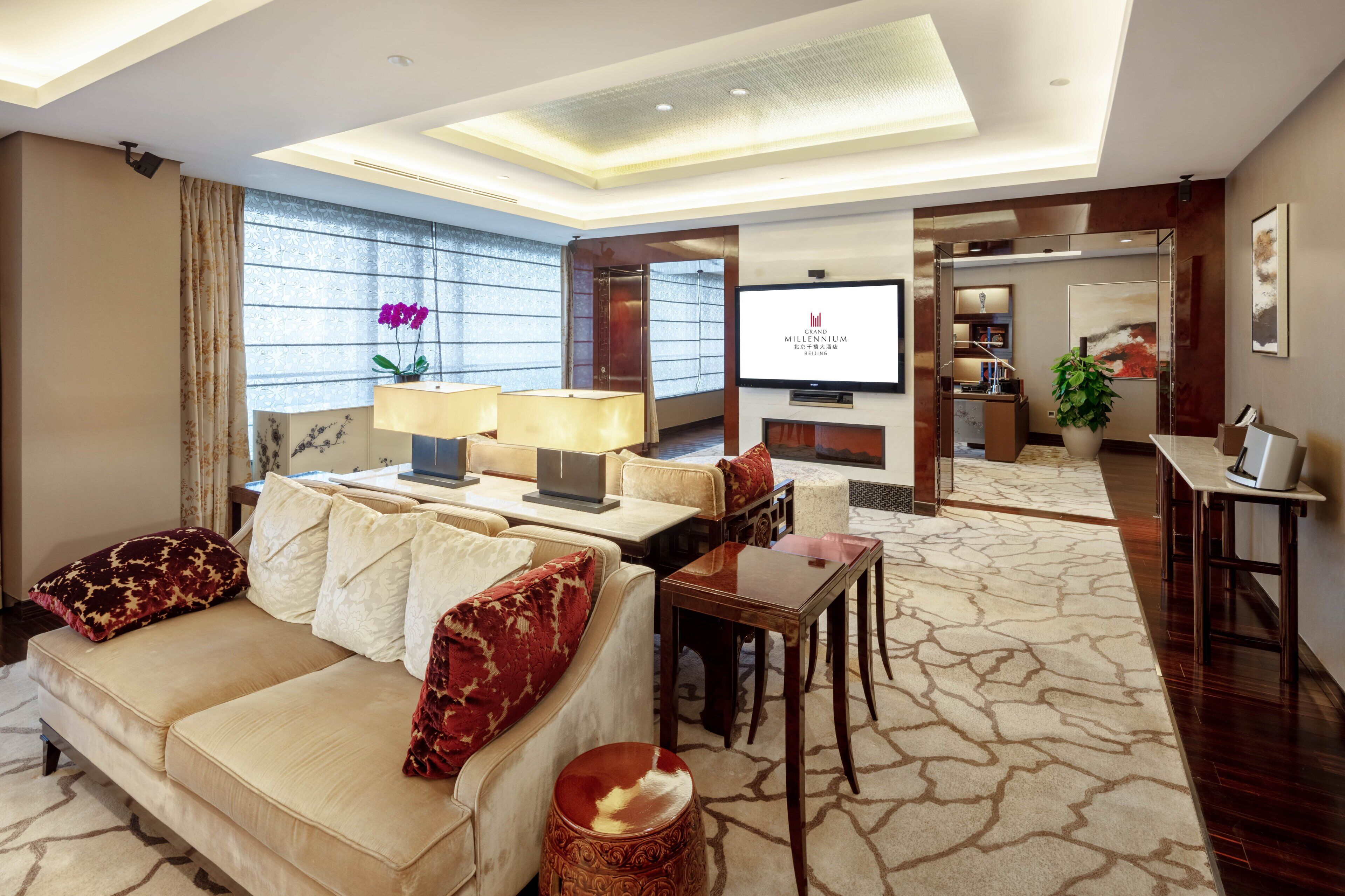 Eine moderne Hotelhalle mit einer Couch, einem Couchtisch und einem Fernseher, der den Namen des Hotels zeigt.