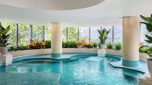 An indoor swimming pool with clear blue water, surrounded by columns and potted plants. - Grand Millennium Beijing (Beijing)