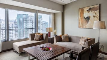 A modern hotel room with a large window, two sofas, a wooden coffee table, and a floor lamp.