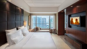 A hotel room with a large bed, a TV mounted on the wall, and a view of the city through the window. - Grand Millennium Beijing (Beijing)