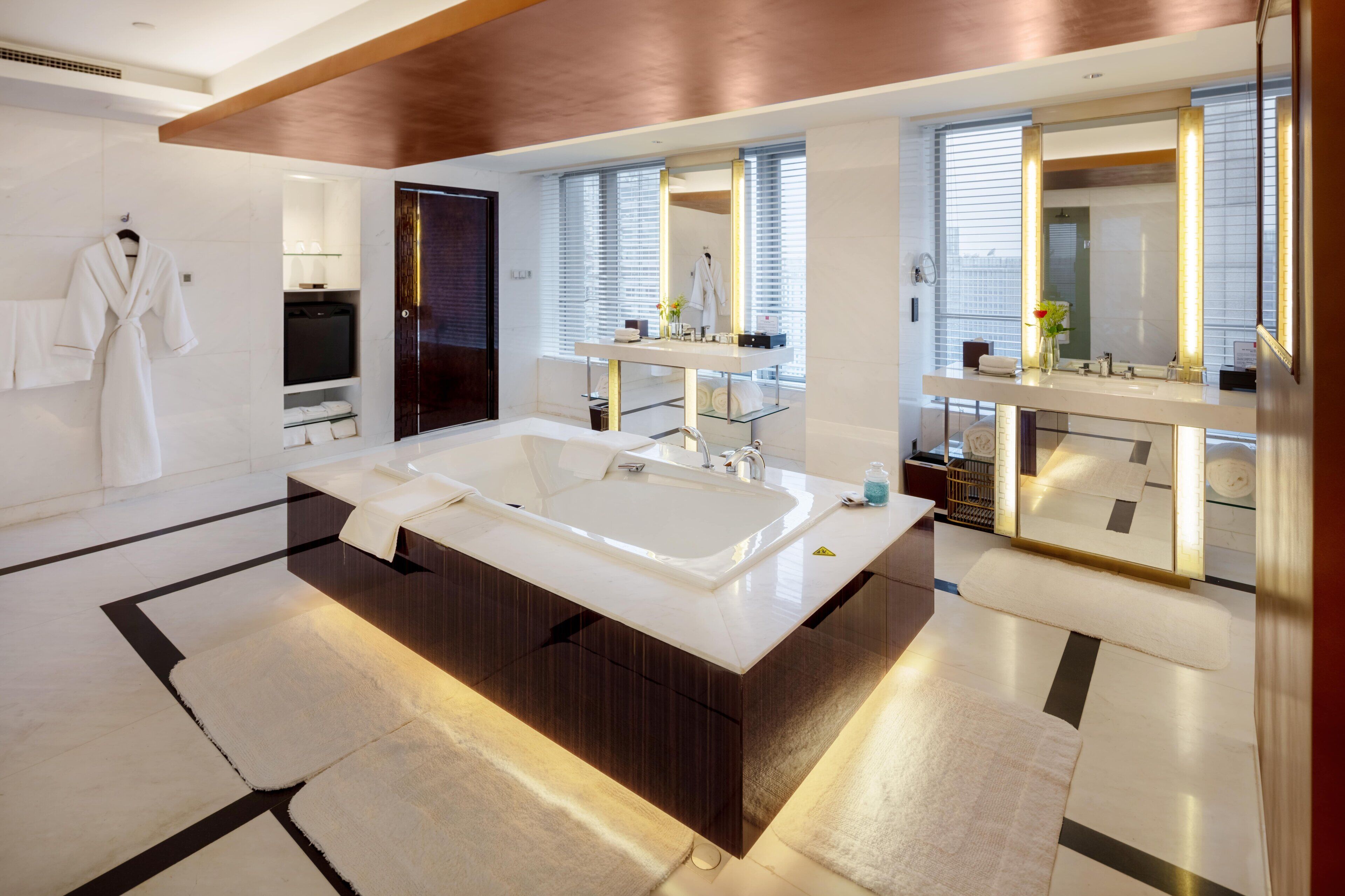 A modern bathroom with a large bathtub, a vanity with a mirror, and a robe hanging on a rack.