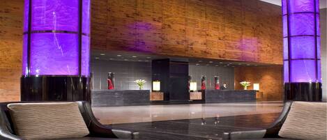 A modern lobby with a reception desk, two sofas, and a coffee table with a vase of flowers.