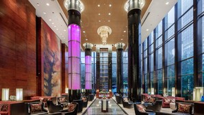 A spacious lobby with modern furnishings, large windows, and a central decorative column. - Grand Millennium Beijing (Beijing)