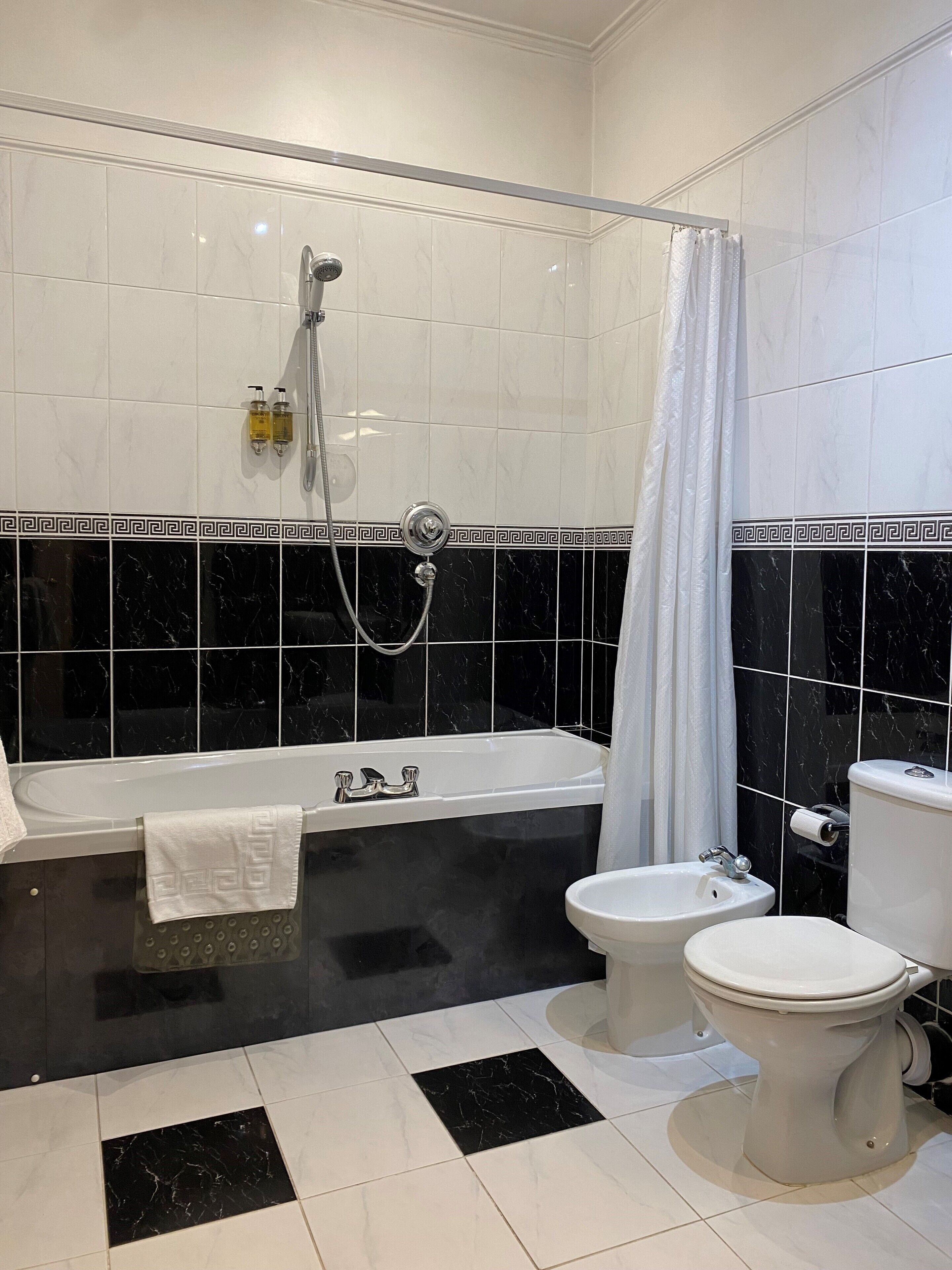 Et badeværelse med badekar, bruser, toilet og bidet.