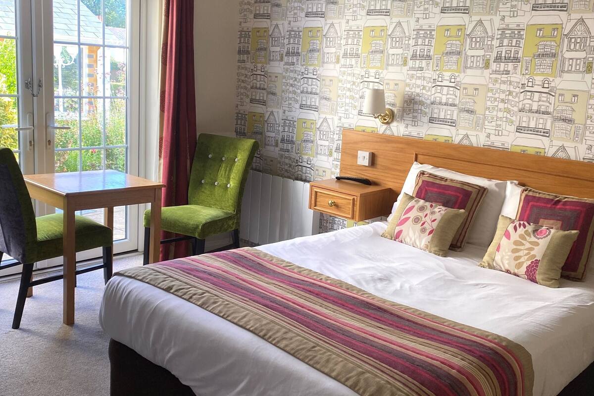 A hotel room with a large bed, a desk, and a chair.