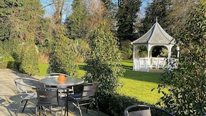 Ein Terrassenbereich im Freien mit Steinböden, Metallstühlen und einem Glastisch.