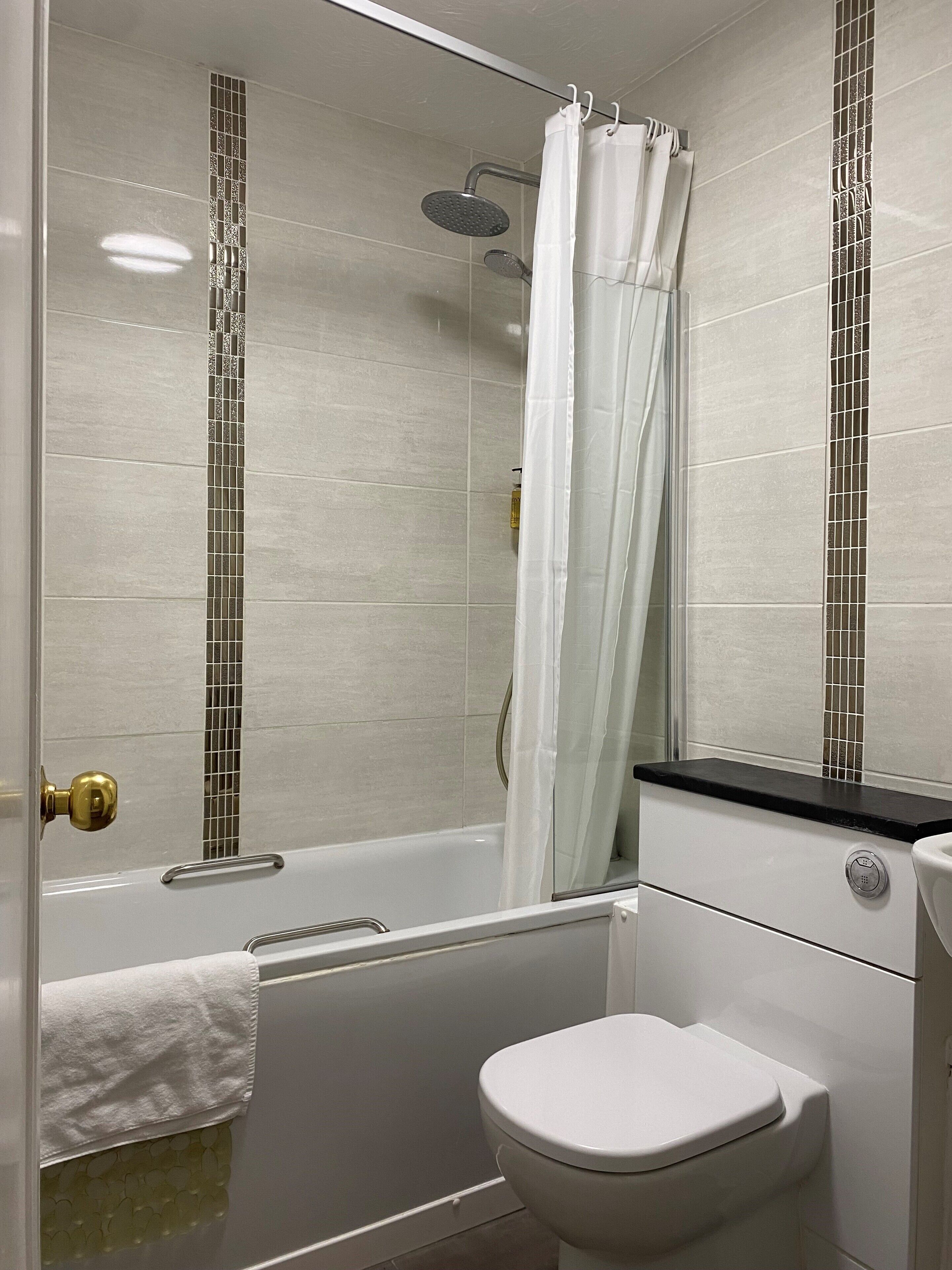 Une salle de bain avec une douche, des toilettes et une baignoire.
