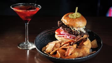 A martini glass and a plate with a burger and chips.