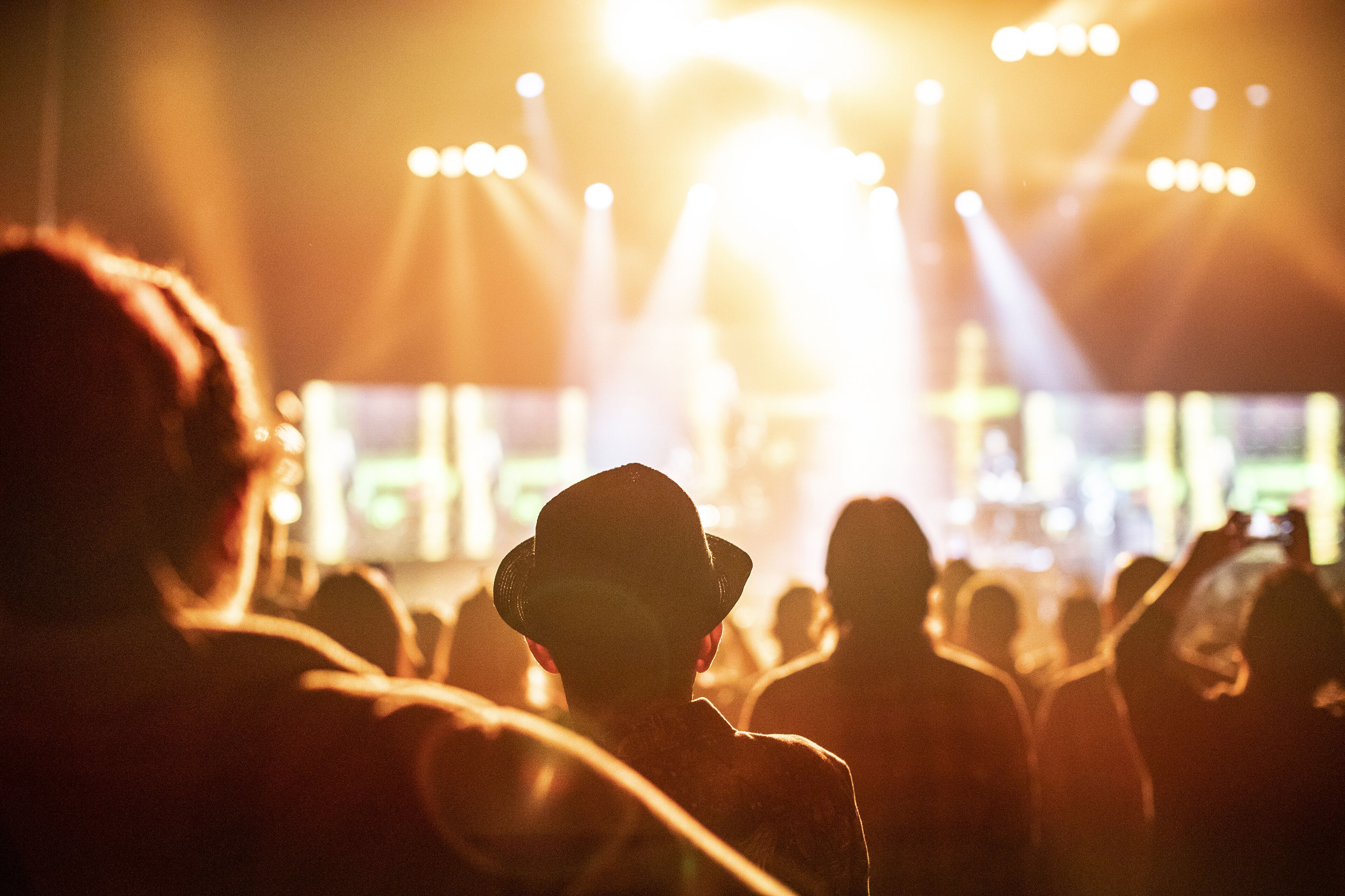 A crowd at an event with bright stage lighting.