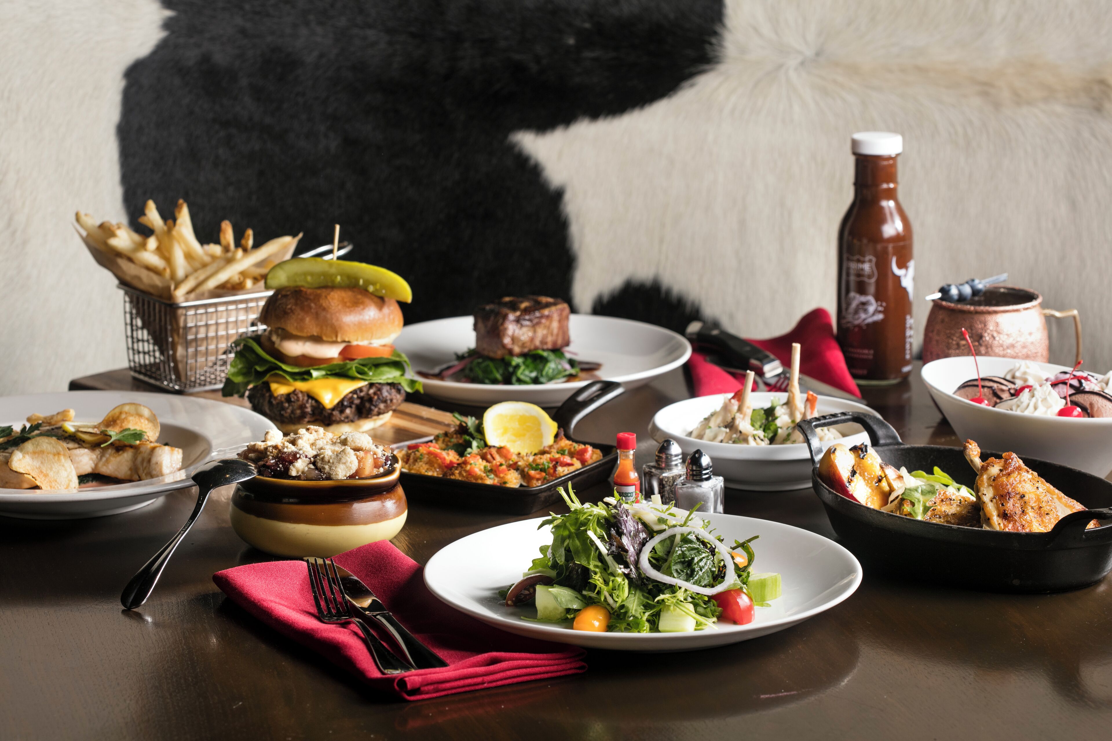 Une variété de plats sont disposés sur la table, notamment un hamburger, une salade et d’autres aliments.