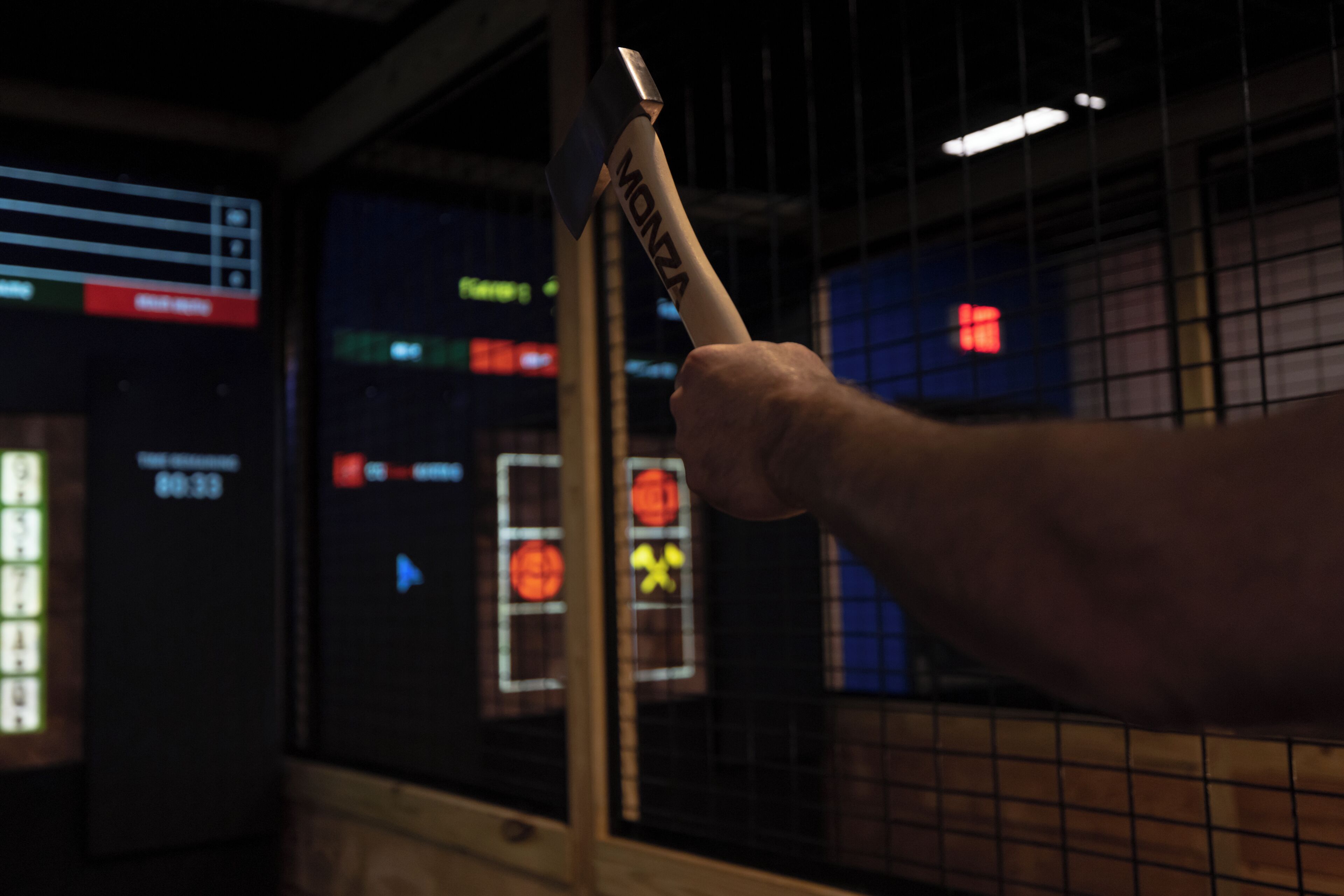 A hand holding a MONZA hammer in front of a control panel with illuminated buttons and indicators.