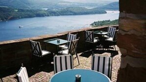 A terrace with outdoor seating overlooking a lake and hills. - Hotel Schloss Waldeck (Waldeck)