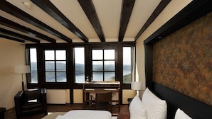 A bedroom with a large bed, a desk, and a view of a lake. - Hotel Schloss Waldeck (Waldeck)