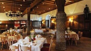 A restaurant with multiple round tables set for dining, wooden beams on the ceiling, and a large pillar in the center. - Hotel Schloss Waldeck (Waldeck)