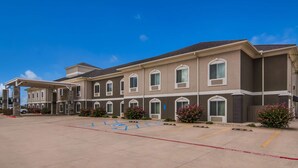 A multi-story hotel with a covered entrance and a parking lot. - Best Western Comanche Inn (Comanche)