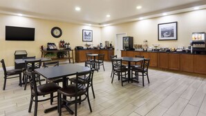 A spacious dining area with multiple tables and chairs, a kitchen counter, and a clock on the wall. - Best Western Comanche Inn (Comanche)