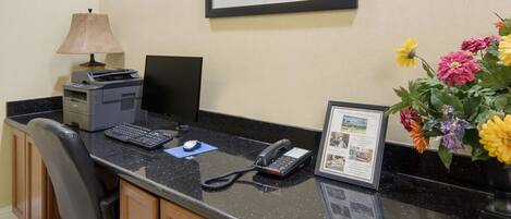 A hotel reception desk with a computer, telephone, and a framed certificate.