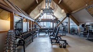 A gym with weightlifting equipment, benches, and kettlebells.