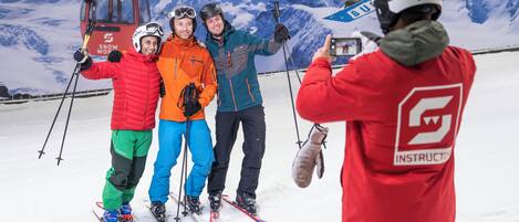 Un grupo de personas esquiando, con un telesilla y montañas nevadas al fondo.