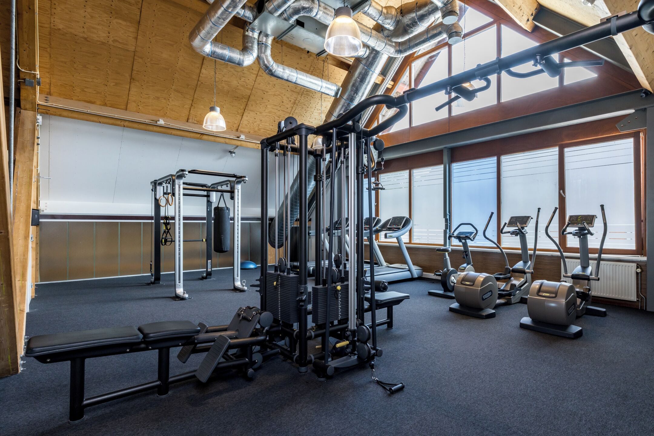 A gym with various exercise equipment, a bench, and a treadmill.