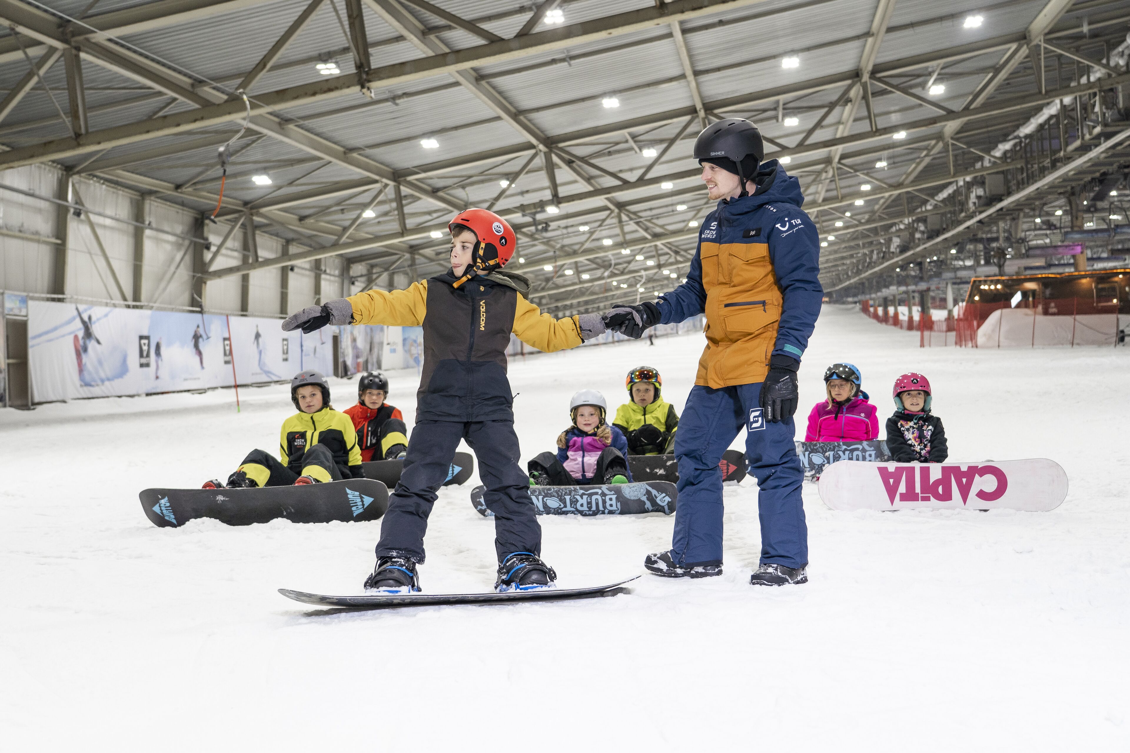 An indoor snowboarding facility with a high ceiling and metal beams.