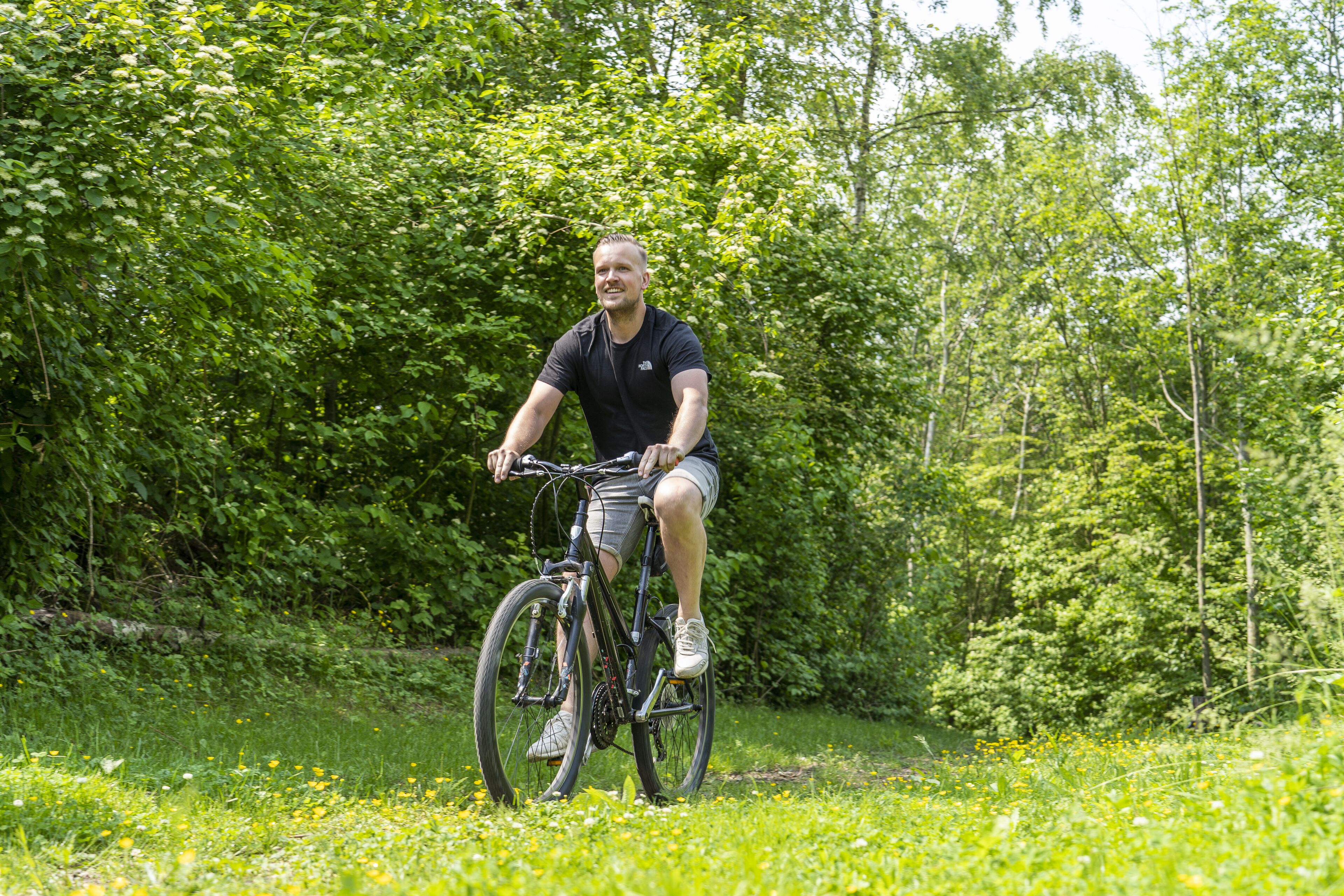 Una persona montando en bicicleta en una zona verde exuberante, con follaje denso al fondo.