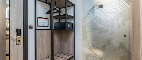 Una habitación de hotel moderna con suelo de madera, un estante metálico negro, un mapa enmarcado en la pared y un mural con mapa del mundo.