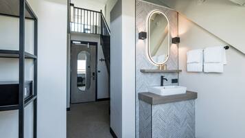 Une salle de bain moderne avec une baignoire sur pieds, un meuble-lavabo avec un miroir et un porte-serviettes.