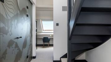 Ein modernes Interieur mit einer Treppe, einem Schreibtisch mit Stuhl und einem Fenster mit Tageslicht.