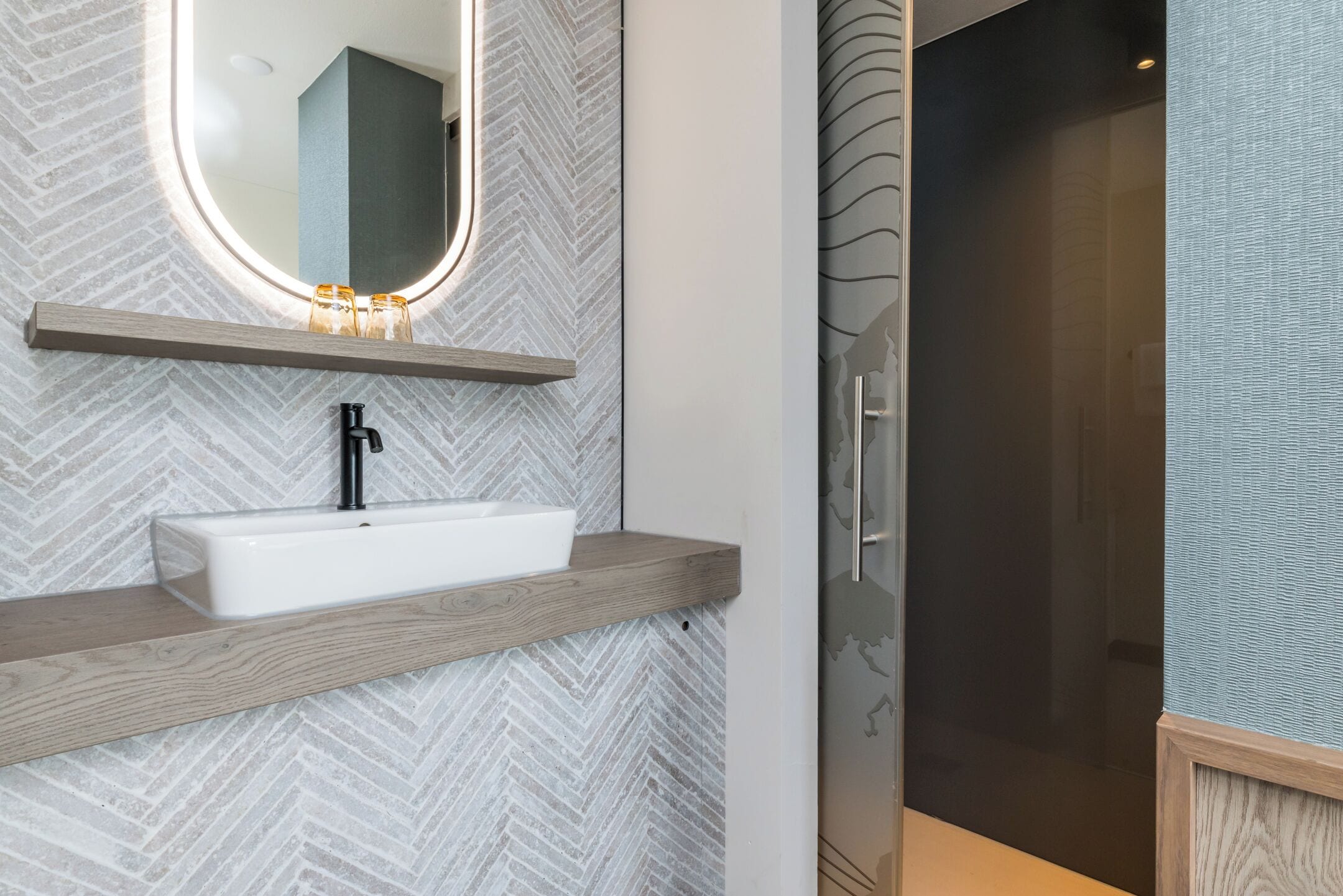 A modern bathroom with a rectangular sink, a mirror with a wooden shelf above, and a shower area with a glass door.