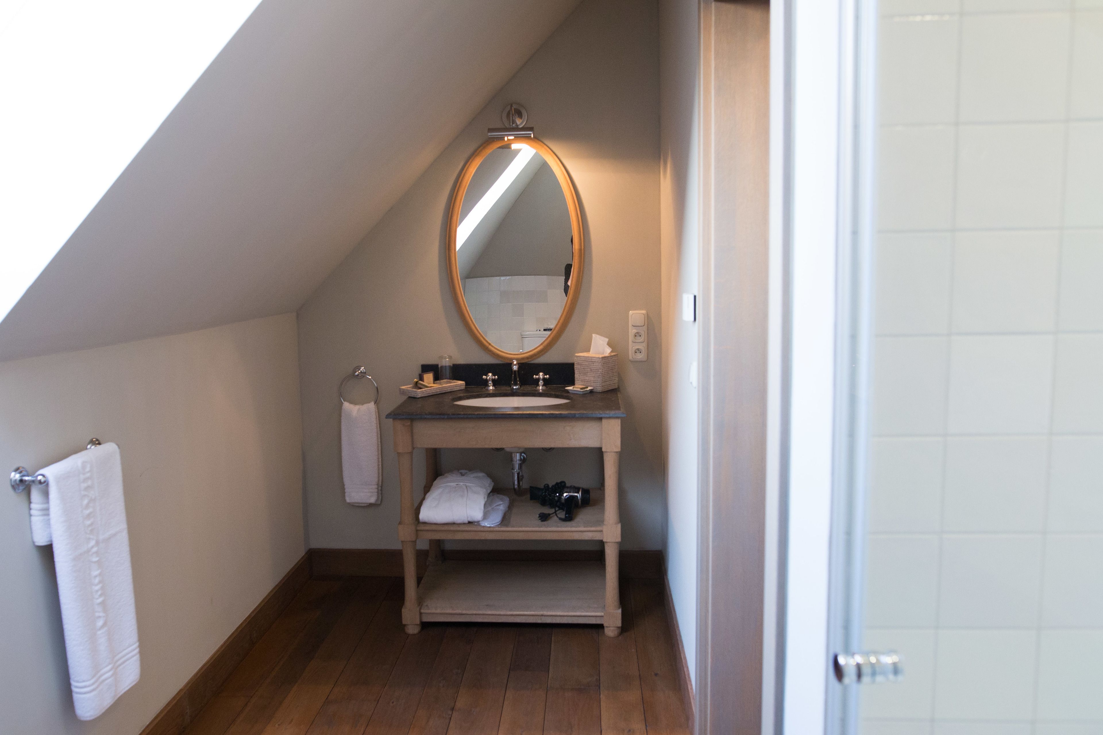 Un baño con tocador de madera, un espejo y un perchero para toallas.