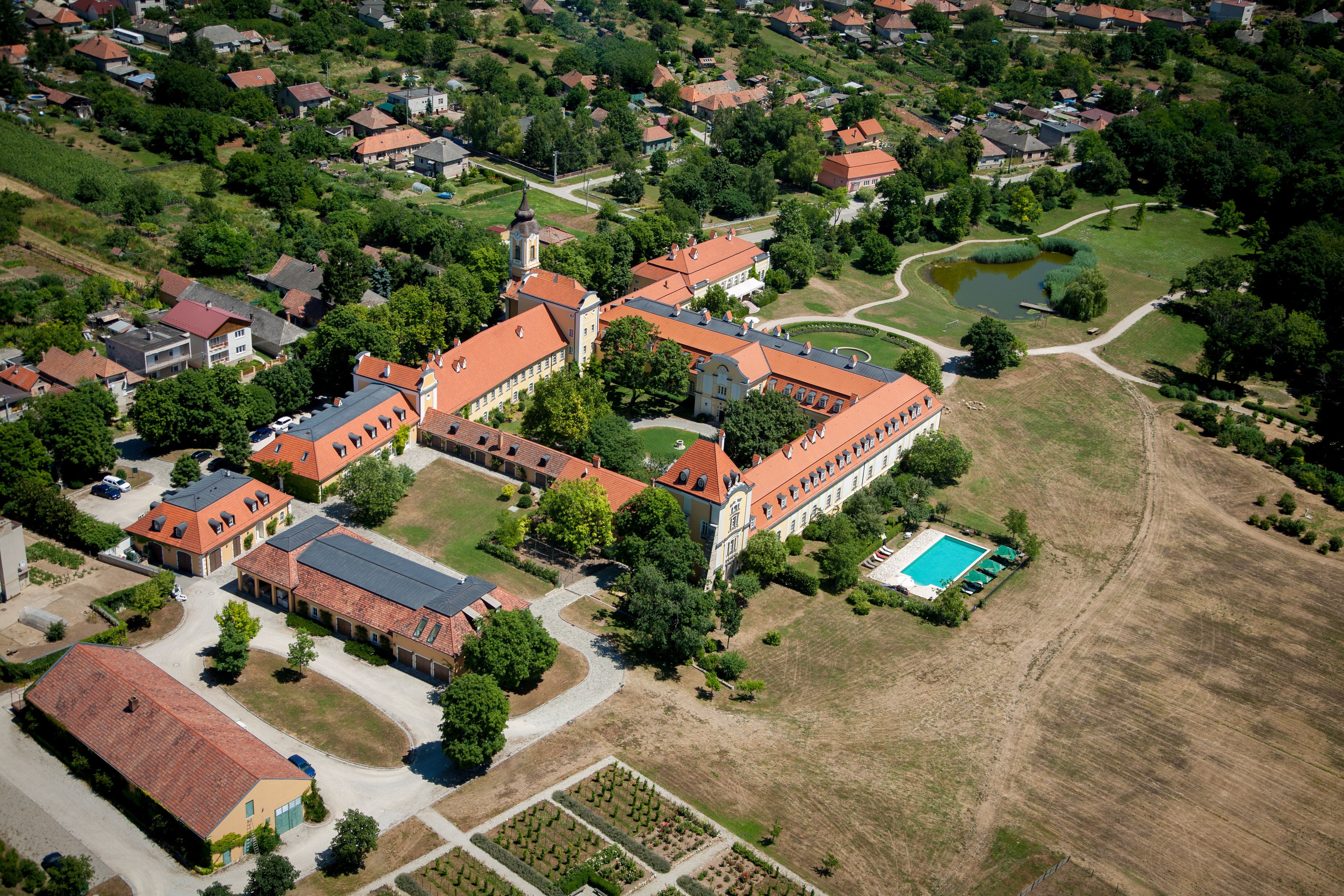 An aerial view of a residential area with a large building featuring a central courtyard and a swimming pool.