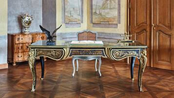 A room with a large ornate desk, a chair, a wooden cabinet, and a large wooden door.