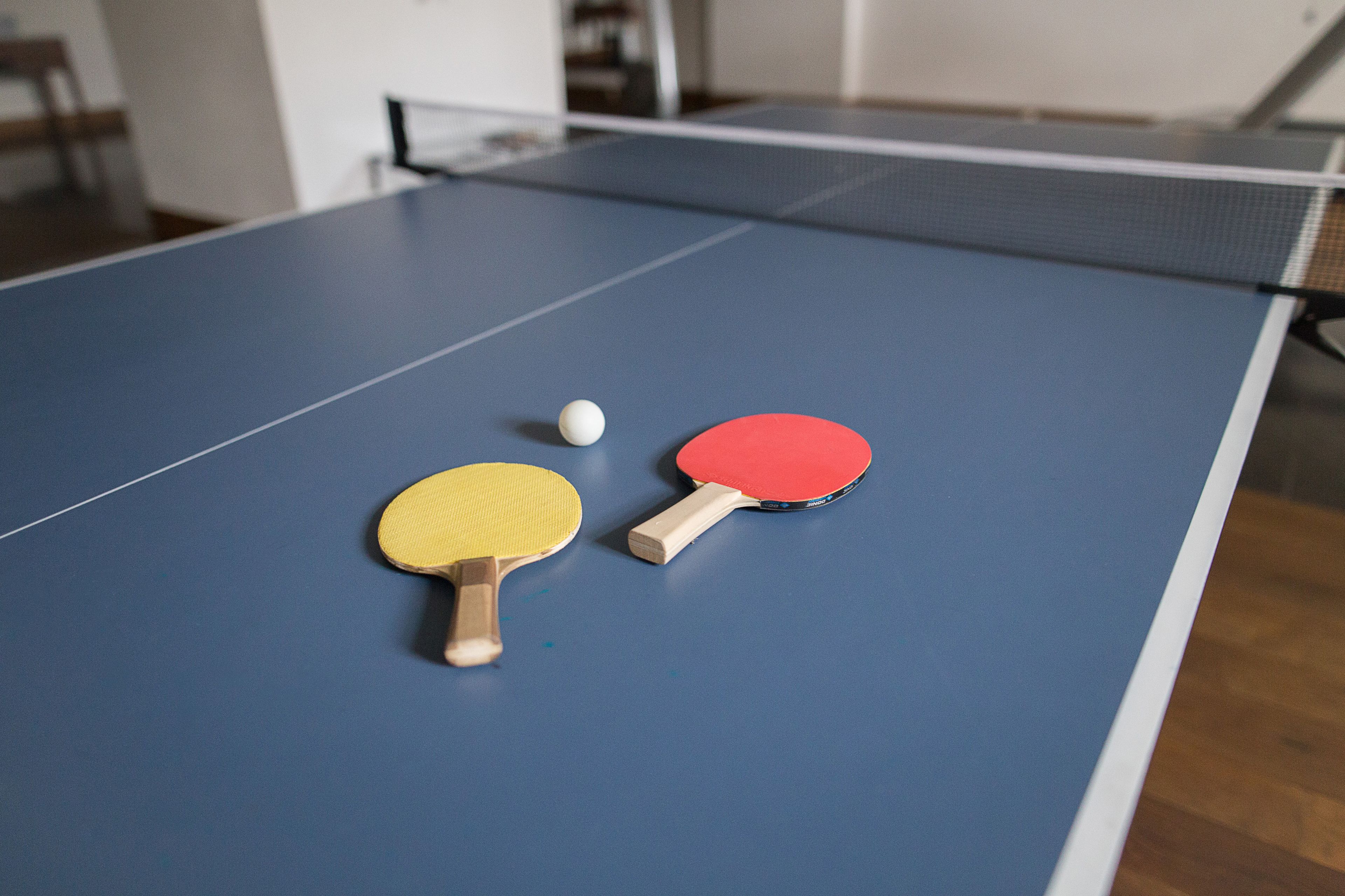 Ett bordtennisbord med två racketar och en boll.