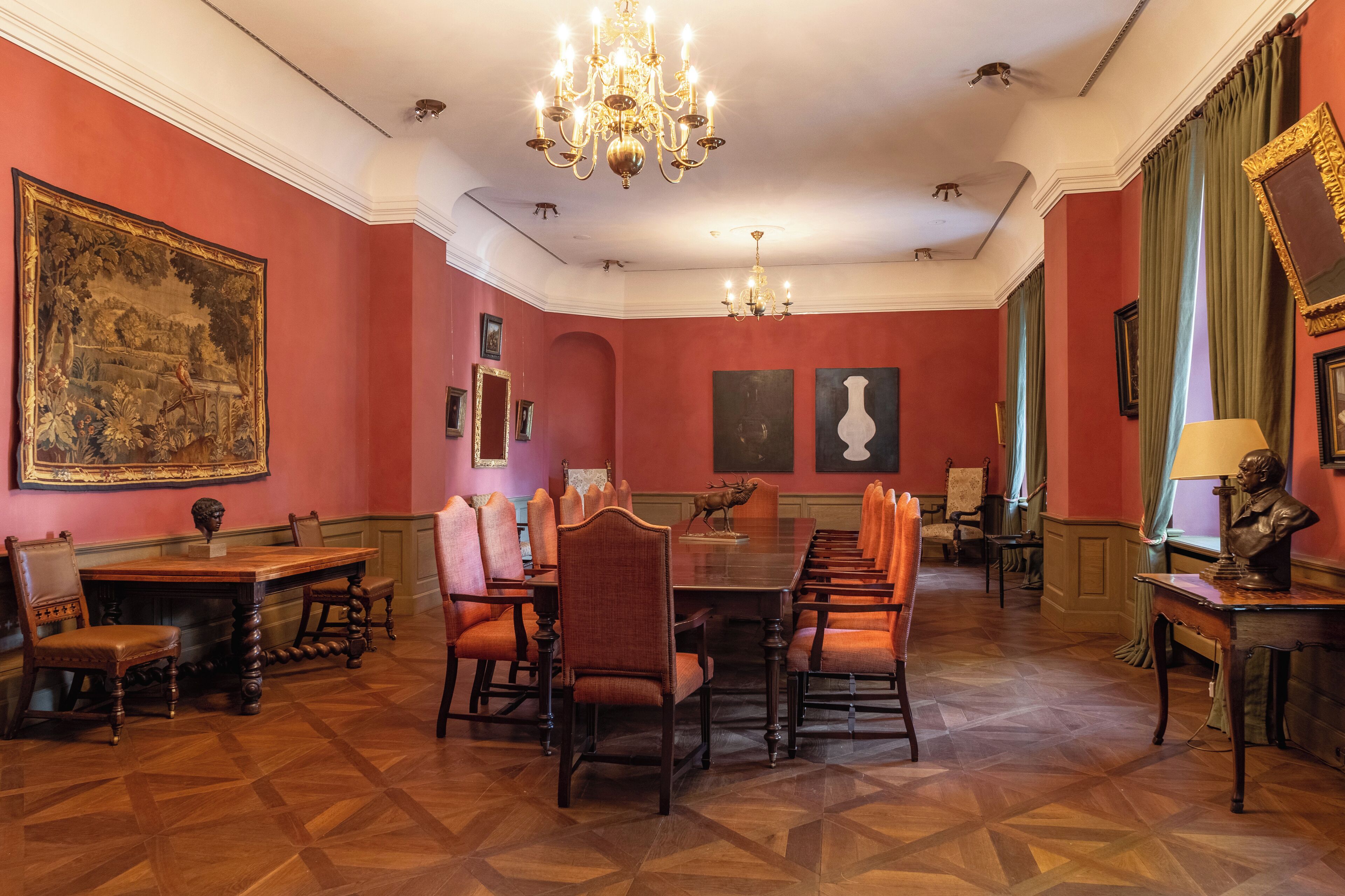 A formal dining room with a long table, multiple chairs, and a chandelier.