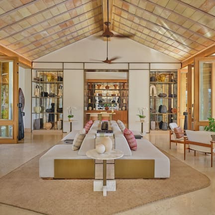 A spacious living area with a high ceiling, a central seating arrangement, and a view of the outdoors.