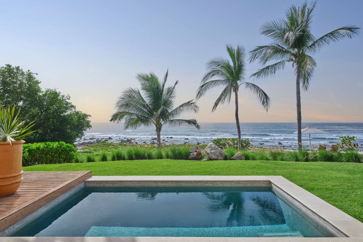 Una piscina con vistas al océano y palmeras.