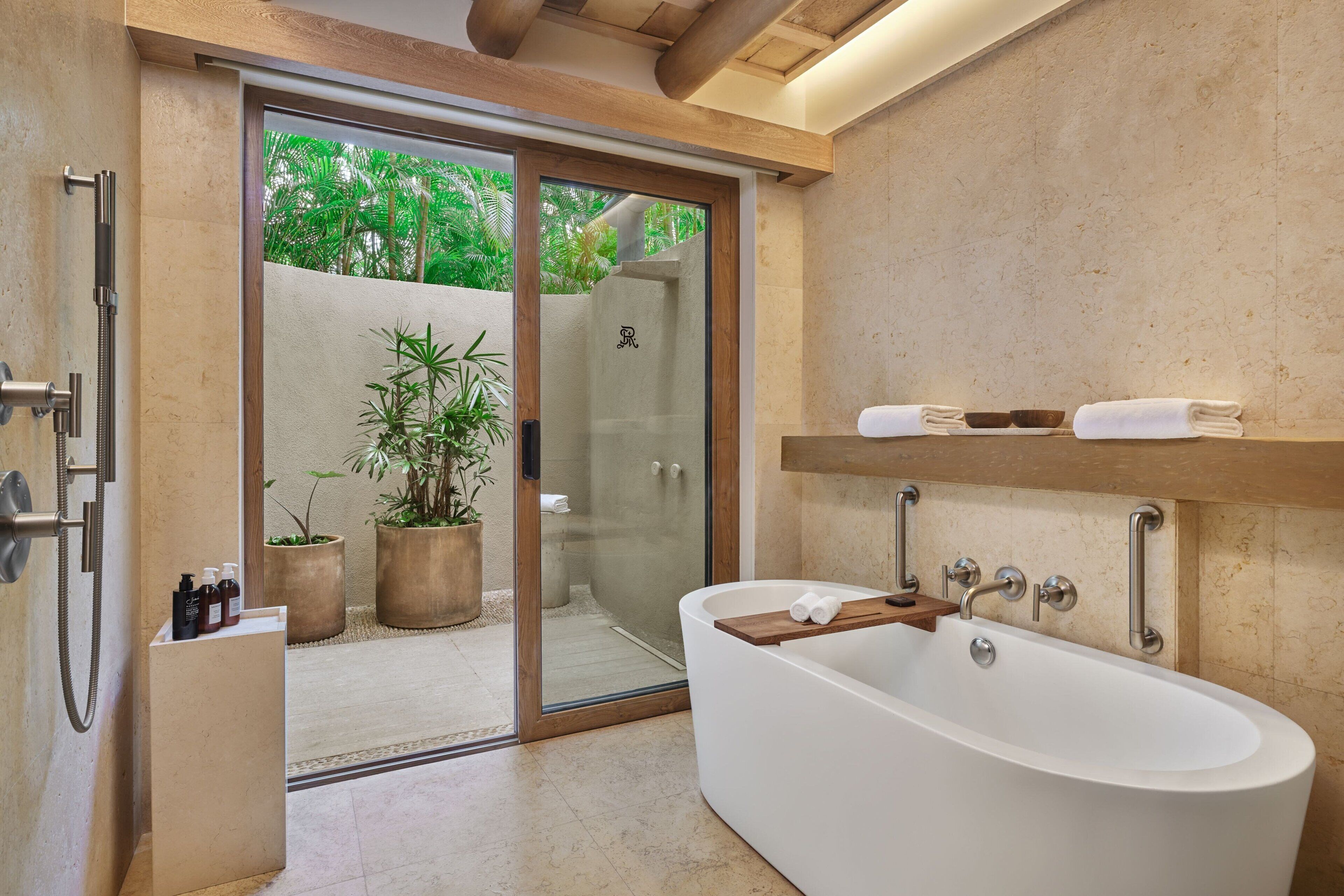 A modern bathroom with a freestanding bathtub, glass shower enclosure, and a wooden shelf with towels.