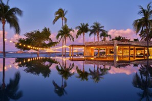 A beachfront resort with a pool reflecting palm trees and a string of lights. - The St. Regis Punta Mita Resort (Punta de Mita)