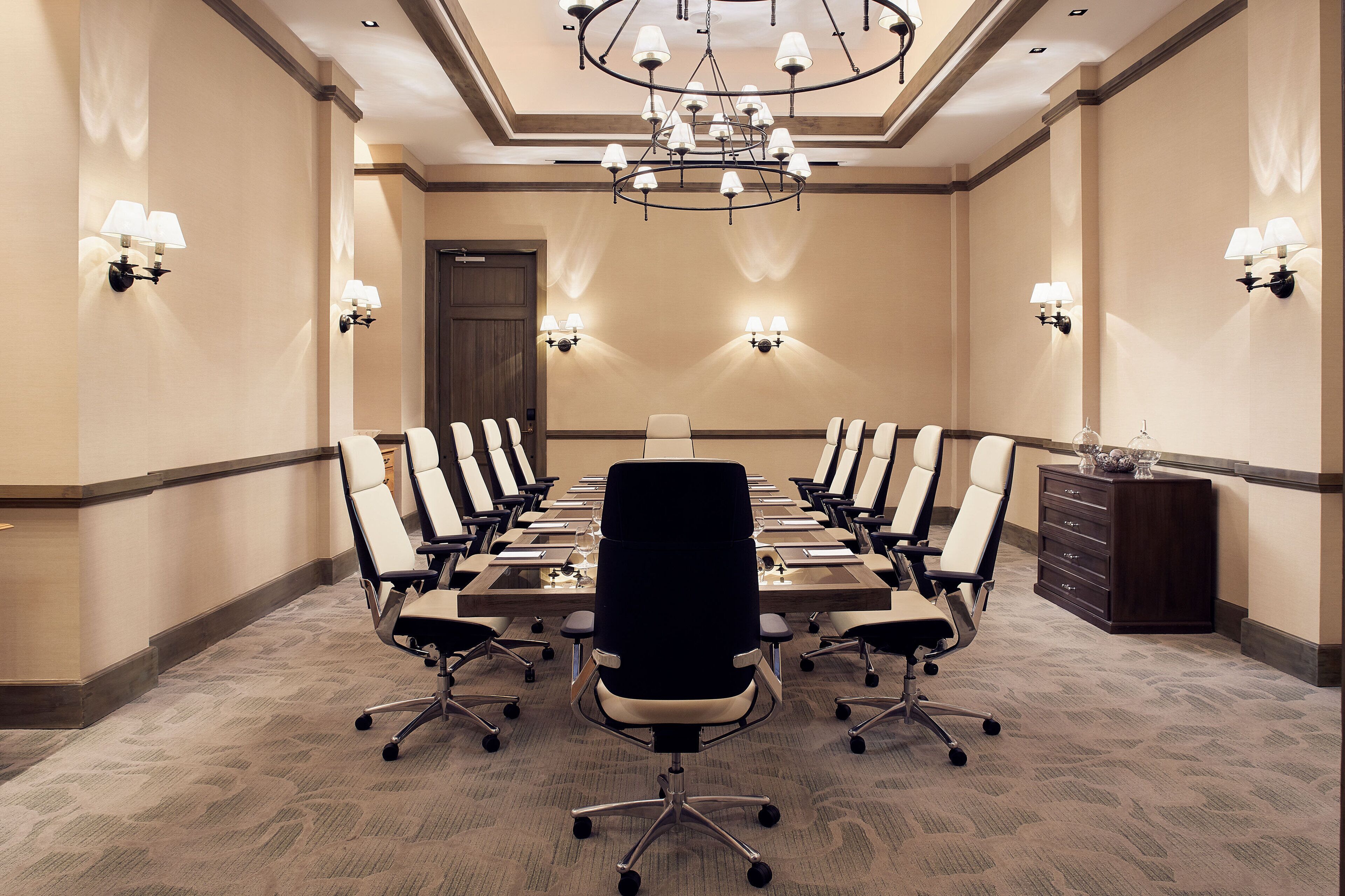 A conference room with a long table, multiple chairs, and a chandelier.
