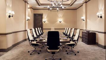 A conference room with a long table, multiple chairs, and a chandelier.