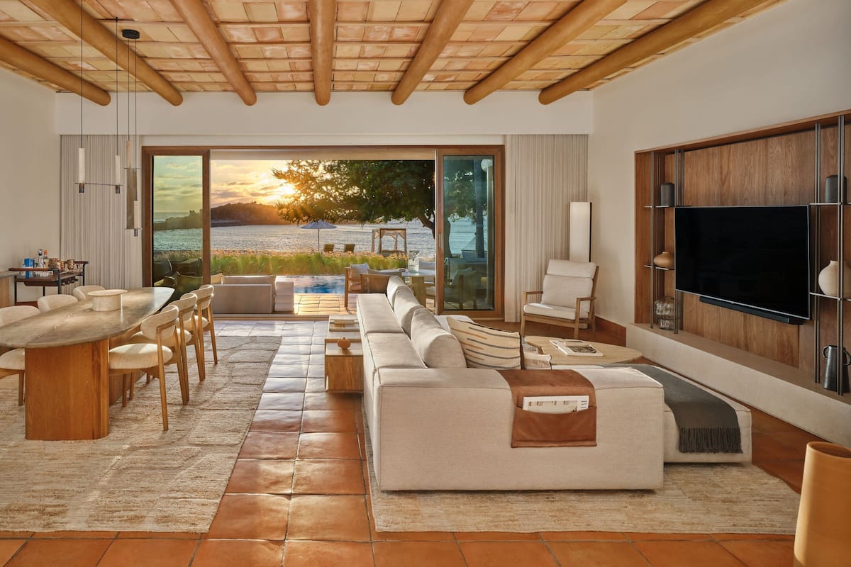 Una sala de estar moderna con un ventanal grande que ofrece vistas panorámicas, un comedor con mesa de madera y una zona de estar acogedora.