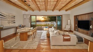 Amplia sala de estar con televisor grande, asientos cómodos, chimenea y vistas al exterior.