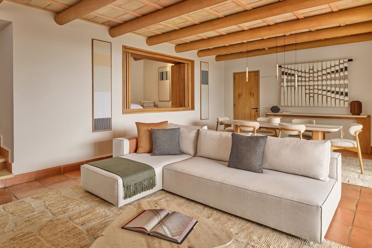 Una sala de estar moderna con un sofá modular, una mesa de centro y un comedor con una mesa de madera y sillas.