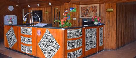 A reception desk with a wooden finish, patterned designs, a clock, and a 'No Smoking' sign.