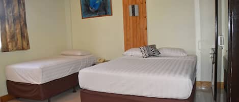 Habitación con dos camas, techo de madera, un cuadro en la pared y una puerta a la derecha.