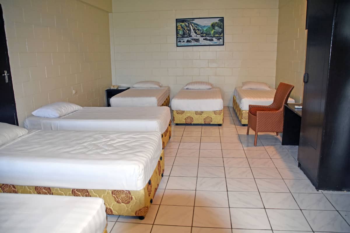 Una habitación de hotel con cuatro camas, una silla y un cuadro en la pared.