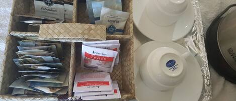 A tray with coffee packets, a box, and two white ceramic cups.