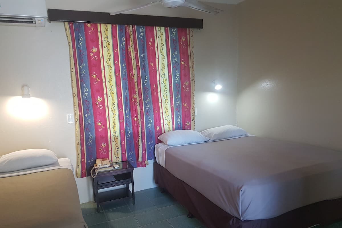 Habitación de hotel con cama, mesita de noche con teléfono y cortina de estampado floral.